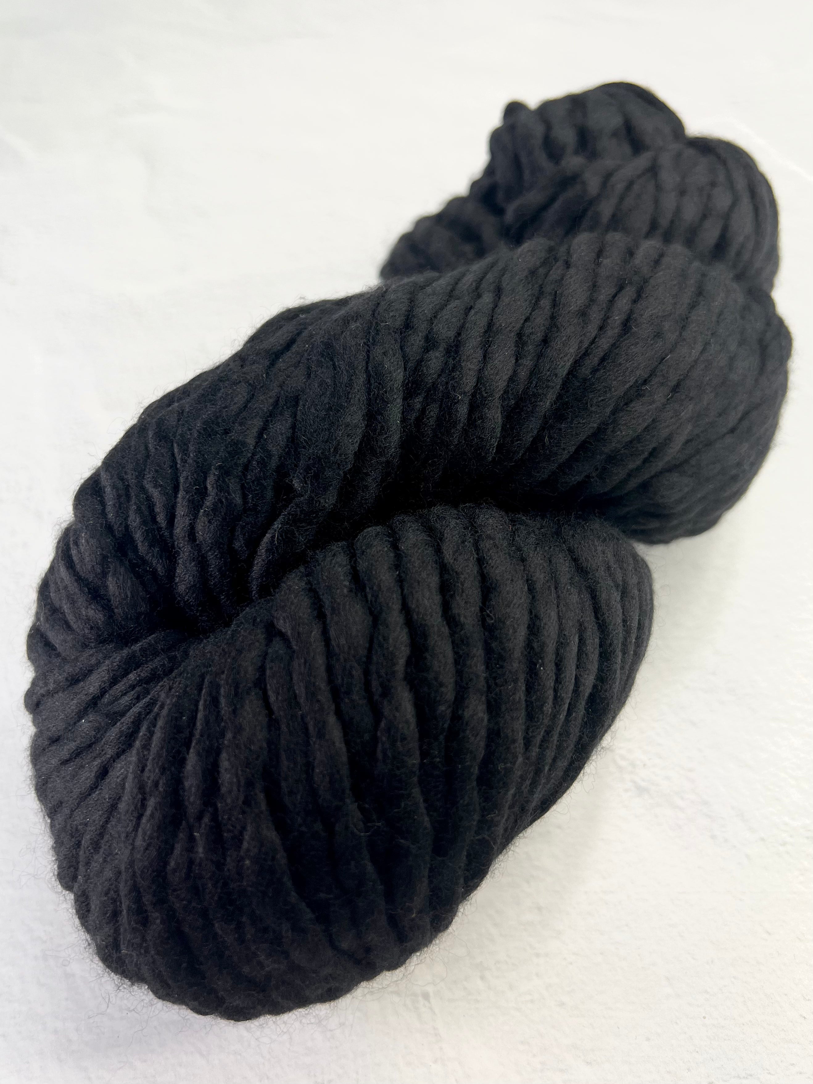 Malabrigo Rasta black merino wool yarn ball, soft and chunky, perfect for knitting and crocheting cozy projects.
