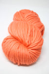 Bright coral Cascade Yarns Magnum bulky yarn ball, showcasing vibrant color and thick texture for knitting or crochet projects.