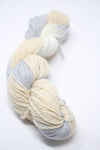 Jade Sapphire Zageo 6 Ply Cashmere yarn in a natural beige color, displayed on a textured background with a beach scene.