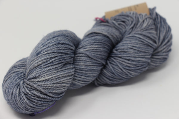 Madelinetosh Tosh DK yarn in Aura color, showing soft, twisted wool skein with rich blue and gray tones.