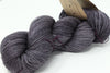 Madelinetosh Tosh DK yarn in a soft grey color, showing the skein with a subtle textured background.