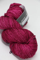 Madelinetosh Tosh DK yarn in Coquette Deux, showing soft pink and purple tones with a smooth, twisted skein.