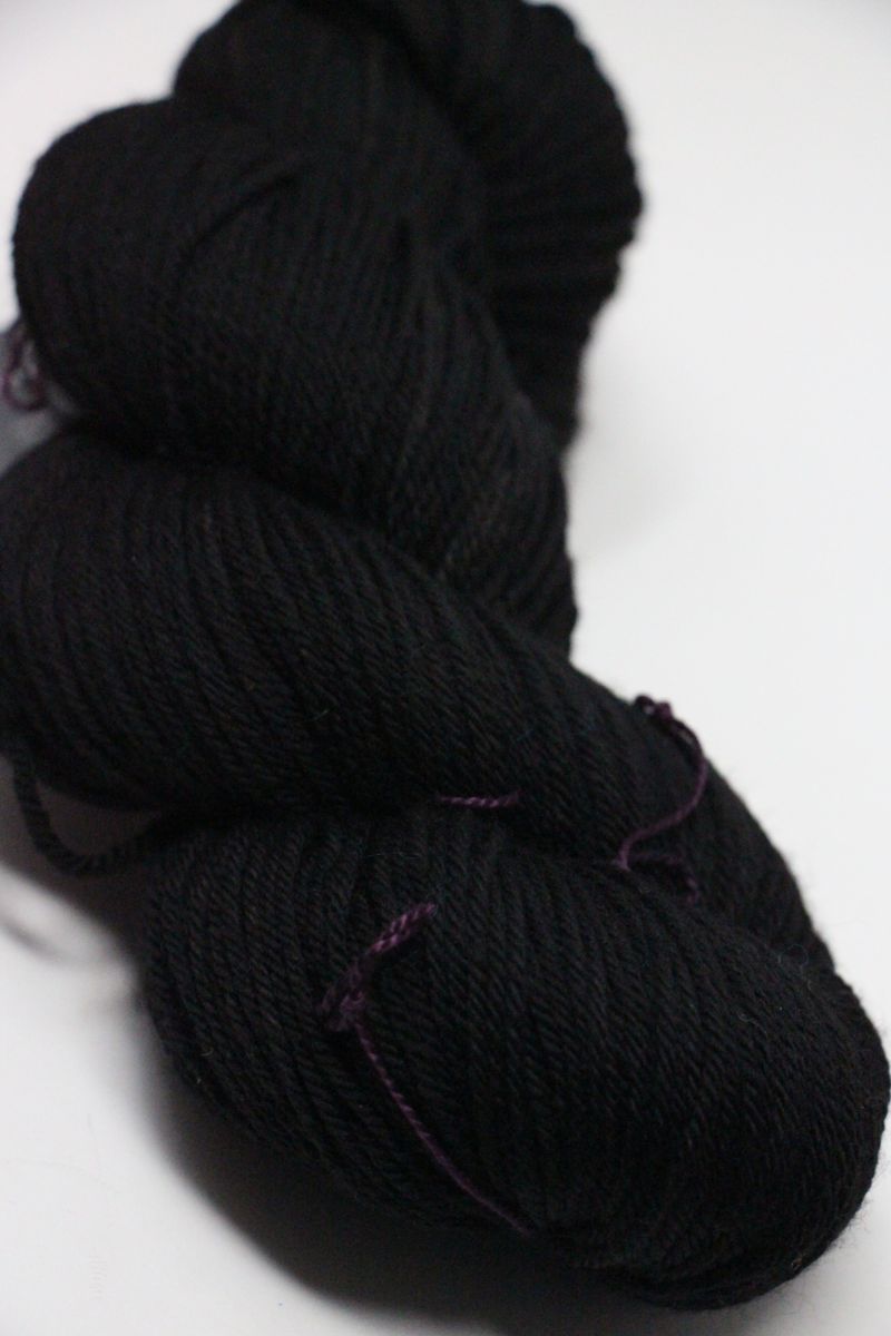 Madelinetosh Tosh DK yarn in Onyx color, showcasing soft, twisted skein of rich black wool for knitting or crocheting projects.