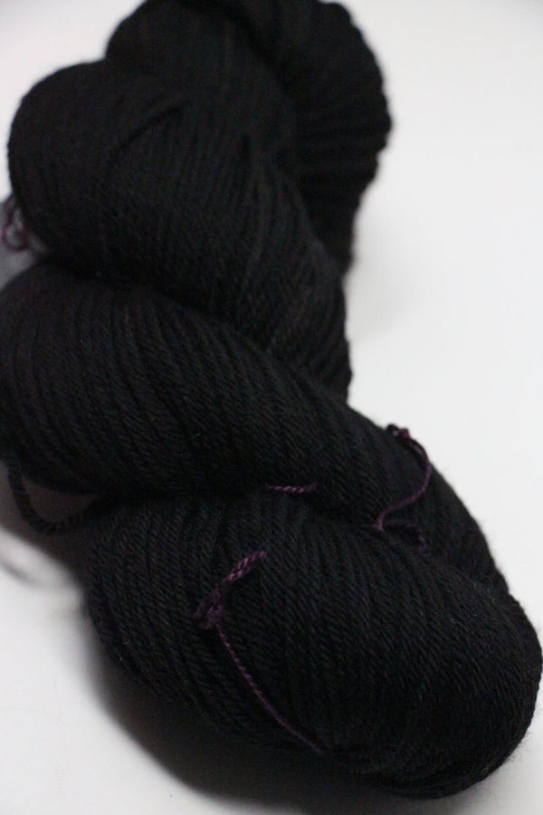 Madelinetosh Tosh DK yarn in Onyx color, showcasing soft, twisted skein of rich black wool for knitting or crocheting projects.