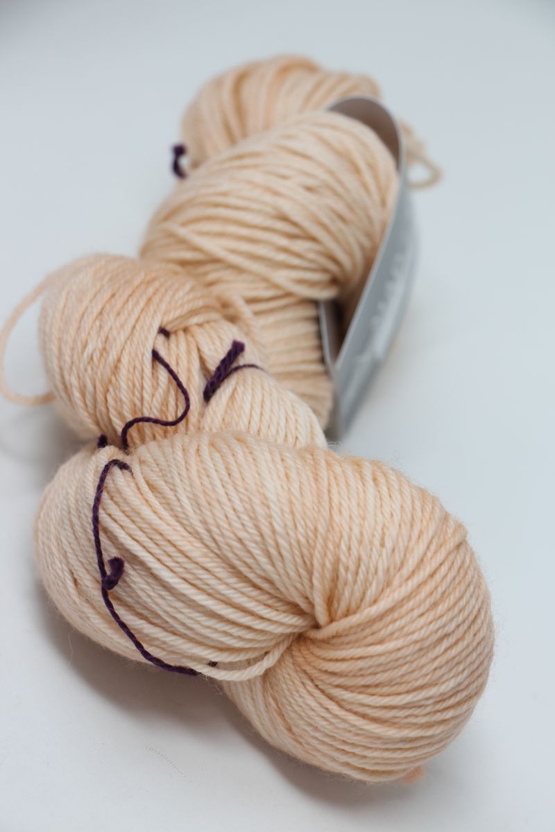 Soft pink and clay-colored Madelinetosh Tosh DK yarn ball, showcasing its rich texture and vibrant color for knitting projects.