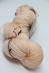 Soft pink and clay-colored Madelinetosh Tosh DK yarn ball, showcasing its rich texture and vibrant color for knitting projects.