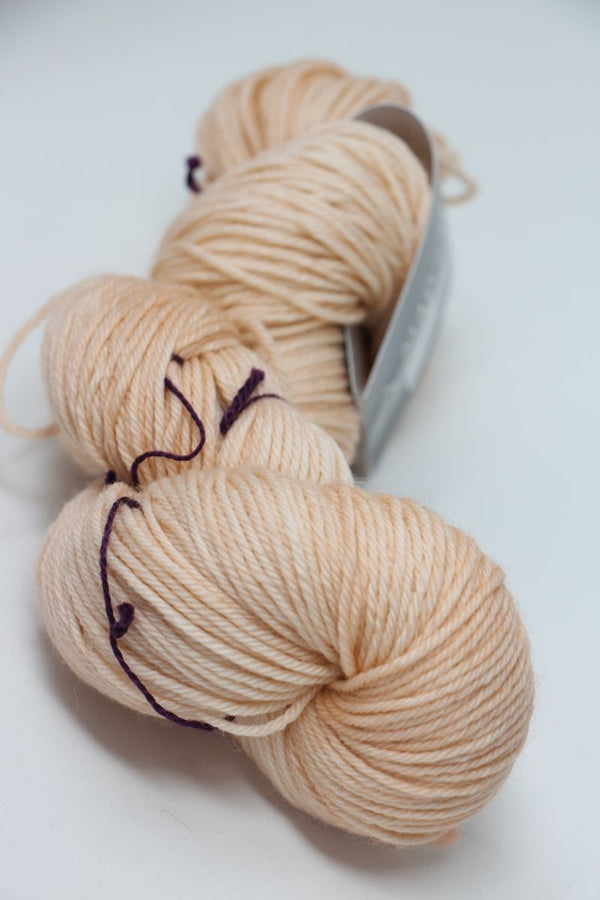 Soft pink and clay-colored Madelinetosh Tosh DK yarn ball, showcasing its rich texture and vibrant color for knitting projects.
