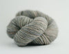 Madelinetosh Tosh DK yarn in a soft, fallen cloud colorway, showcasing the wool fiber and vibrant, earthy tones.