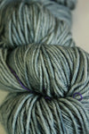 Close-up of Madelinetosh Tosh DK yarn in Aura color, showcasing soft, spun wool fibers with vibrant, variegated blue and green tones.