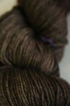 Madelinetosh Tosh DK yarn in pecan hull color, soft wool fiber, shown as a close-up of the skein's rich, warm brown hue.