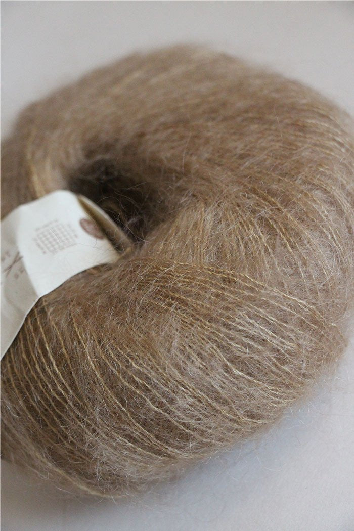 Rowan Kidsilk Haze yarn in a soft mud color, showing the delicate, lightweight fiber with subtle sheen and fine texture.