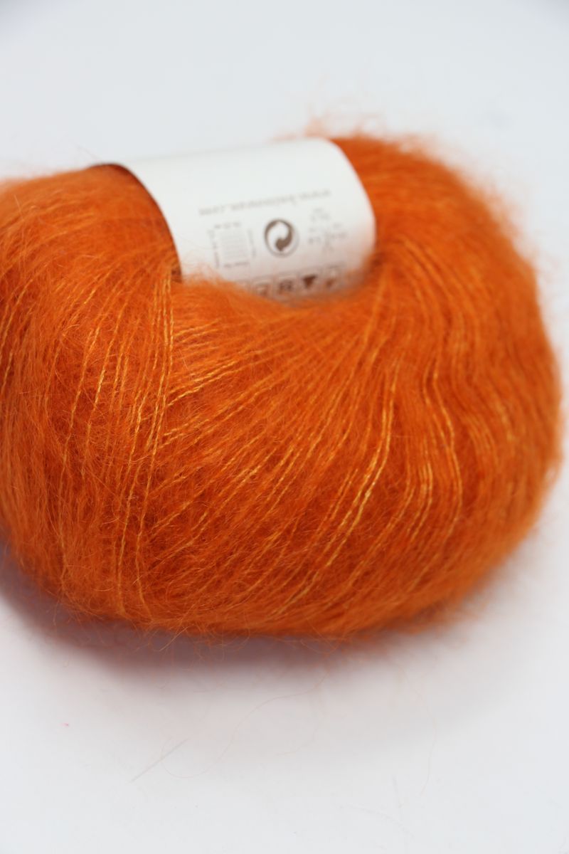Close-up of Rowan Kidsilk Haze yarn in Golden Poppy color, showcasing soft, delicate silk and mohair fibers with a subtle sheen.