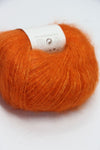 Close-up of Rowan Kidsilk Haze yarn in Golden Poppy color, showcasing soft, delicate silk and mohair fibers with a subtle sheen.