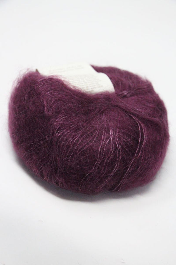 Multicolored Rowan Kidsilk Haze yarn skein in soft pink, purple, and beige tones, ideal for delicate knitting and crochet projects.