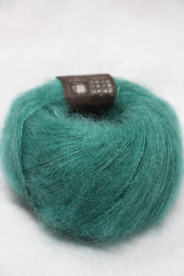 Soft Rowan Kidsilk Haze yarn in a shimmering gem color, showing a close-up of the delicate, lightweight fiber with a subtle sheen.