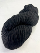 Malabrigo Rasta black merino wool yarn ball, soft and chunky, perfect for knitting and crocheting cozy projects.