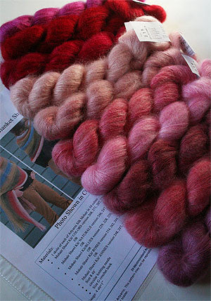 Artyarns Silk Mohair Blanket Knitting Kit with pink and rose-colored yarns, displayed with knitting needles and pattern instructions.