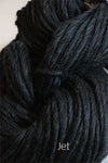 Cascade Yarns Magnum bulky yarn in a rich jet black color, shown in a close-up of soft, thick yarn strands.