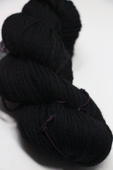 Madelinetosh Tosh DK yarn in Onyx color, showcasing soft, twisted skein of rich black wool for knitting or crocheting projects.