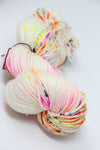 Madelinetosh Tosh DK yarn in Theradness color, soft knitted skein of dark purple and green tones on a white background.
