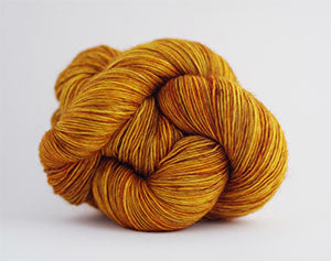 Madelinetosh Tosh DK yarn in Daffodil, soft warm yellow color, showcasing a close-up of the textured yarn skein.