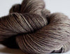 Madelinetosh Tosh DK yarn in a soft, multicolored skein with subtle shades of pink, purple, and cream, ideal for knitting or crochet projects.