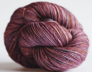 Close-up of Madelinetosh Tosh DK yarn in vibrant kilim colorway, showing soft, twisted wool fibers suitable for knitting and crochet projects.