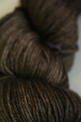 Madelinetosh Tosh DK yarn in pecan hull color, soft wool fiber, shown as a close-up of the skein's rich, warm brown hue.
