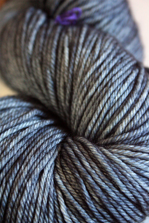 Madelinetosh Tosh DK yarn in a rich, variegated colorway, showing the soft, twisted wool fiber close-up.