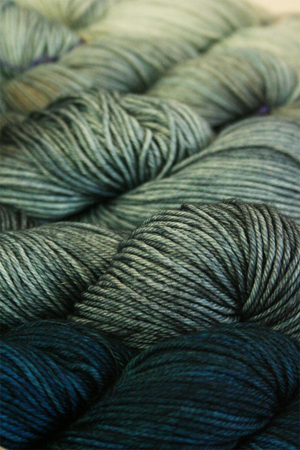Madelinetosh Tosh DK yarn in Deep Druid, a rich, variegated colorway with deep greens and earthy tones.