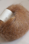 Close-up of Rowan Kidsilk Haze yarn in fudge color, showing soft, delicate fiber with a slightly fuzzy texture.