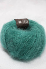 Soft Rowan Kidsilk Haze yarn in a shimmering gem color, showing a close-up of the delicate, lightweight fiber with a subtle sheen.