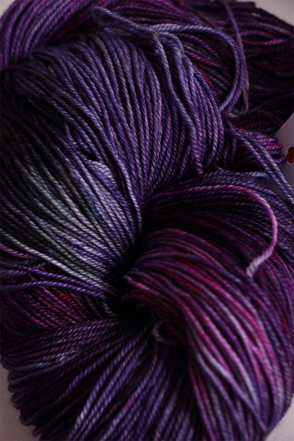 Close-up of Zen Yarn Garden Serenity 20 fingering weight yarn in petunia color, showing soft, vibrant purple fibers and texture.