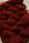 Fingering weight yarn from Zen Yarn Garden's Serenity 20 collection in a vibrant saffron color, showing soft, smooth fiber texture.