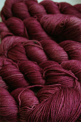 Fingering weight yarn from Zen Yarn Garden's Serenity 20 collection in soft blush pink, showcasing smooth, twisted fibers.