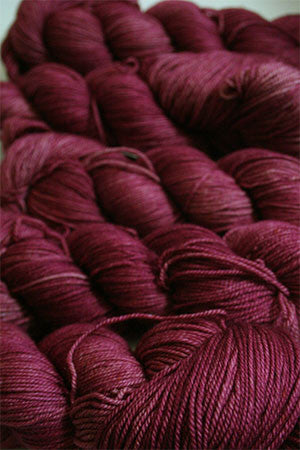 Fingering weight yarn from Zen Yarn Garden's Serenity 20 collection in soft blush pink, showcasing smooth, twisted fibers.