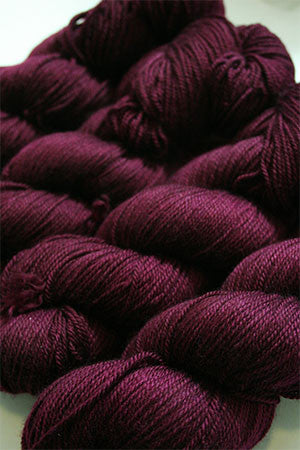 Fingering weight yarn from Zen Yarn Garden's Serenity 20 collection in rich merlot color, showcasing soft fiber and smooth texture.