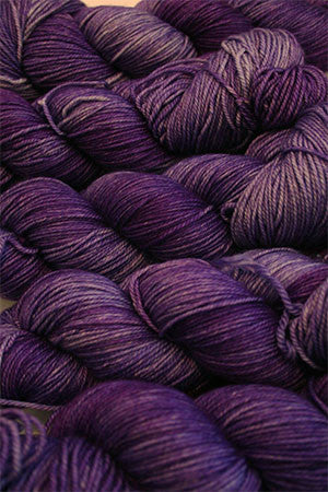 Fingering weight yarn by Zen Yarn Garden, Serenity 20 in pansies colorway, showcasing soft, variegated purple and yellow hues.