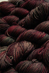 Fingering weight yarn from Zen Yarn Garden's Serenity 20 collection in soft pink and purple tones, showing the yarn's texture and color.