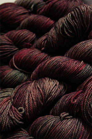 Fingering weight yarn from Zen Yarn Garden's Serenity 20 collection in soft pink and purple tones, showing the yarn's texture and color.